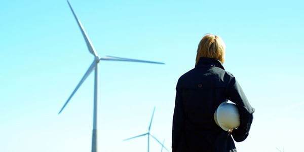 Renewable energy expert looks towards a wind turbine and considers project insurance 