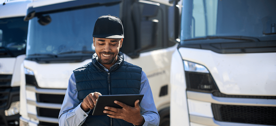 Man with iPad in front of fleet of lorries