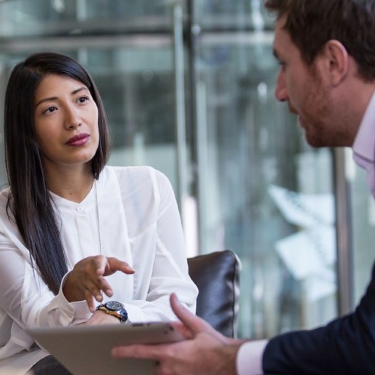 Solicitor PI renewal discussion between two business professionals in an office, reviewing information on a tablet