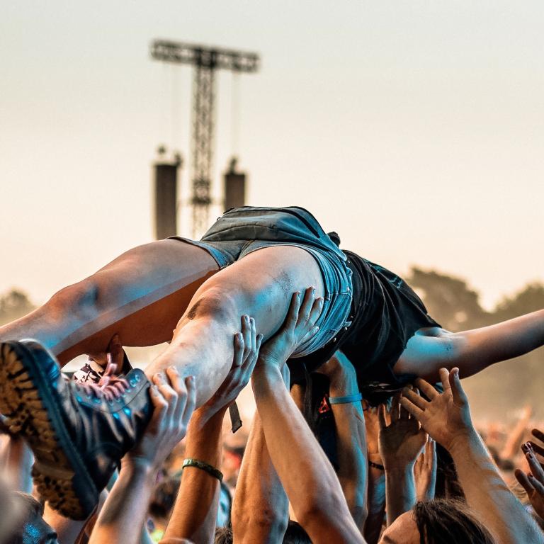 Martyn’s Law UK Guidance 2026 concept image showing a person crowd-surfing above raised hands at an outdoor music festival.