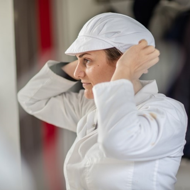 Lady adjusting her cap in a food kitchen